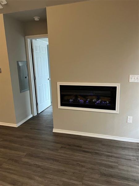 Detailed view of electric panel, baseboards, wood finished floors, and a smoke detector