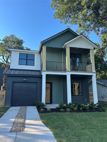 View of front facade with a balcony, a standing seam roof, driveway, a metal roof, and board and batten siding View of front facade with a balcony, a standing seam roof, driveway, a metal roof, and board and batten siding