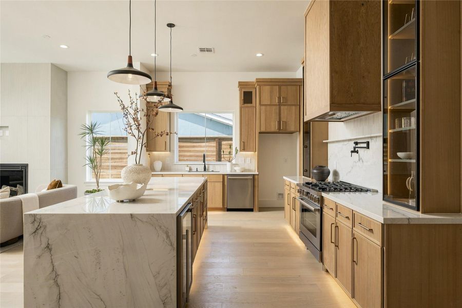 Custom Midnight Glass Towers frame the Bosch range, complemented by a white oak vent hood and illuminated cabinetry that gives the kitchen a distinctly tailored, furniture-like quality.