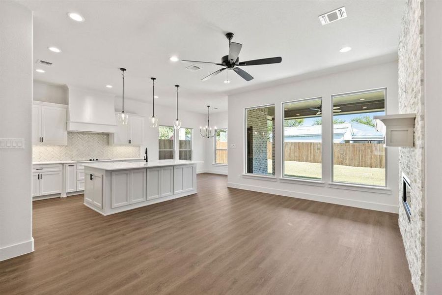 Kitchen featuring white cabinets, pendant lighting, a chandelier, tasteful backsplash, and dark wood-style flooring