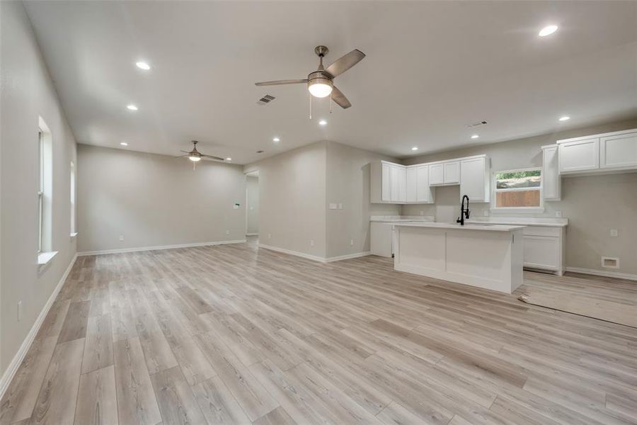 Unfurnished living room with sink, light hardwood / wood-style flooring, and ceiling fan