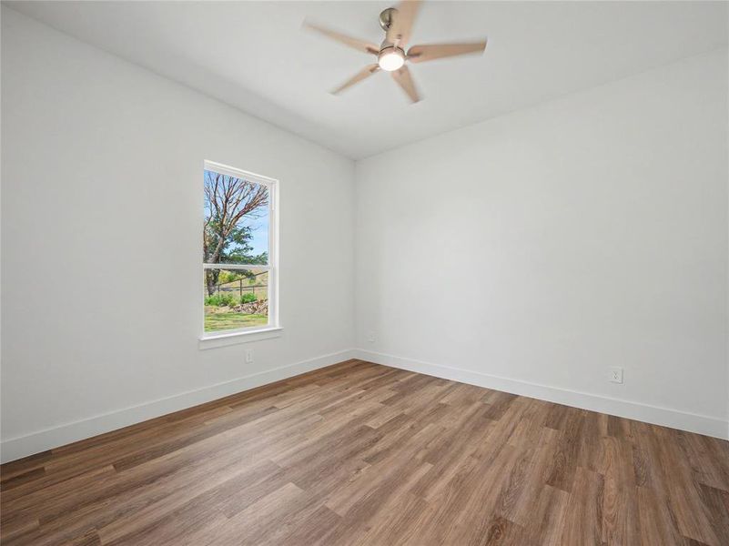 Room featuring wood-finish flooring, crisp white walls, and a contemporary ceiling fan