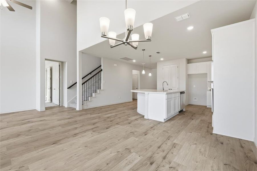 Kitchen featuring a chandelier, a kitchen island with sink, light wood-style floors, hanging light fixtures, and white cabinets Kitchen featuring a chandelier, a kitchen island with sink, light wood-style floors, hanging light fixtures, and white cabinets