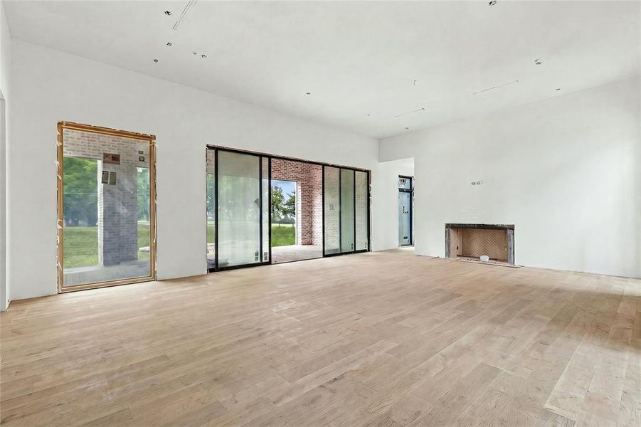 Spacious interior featuring wood-finish flooring, a contemporary fireplace opening, and expansive glass sliding doors