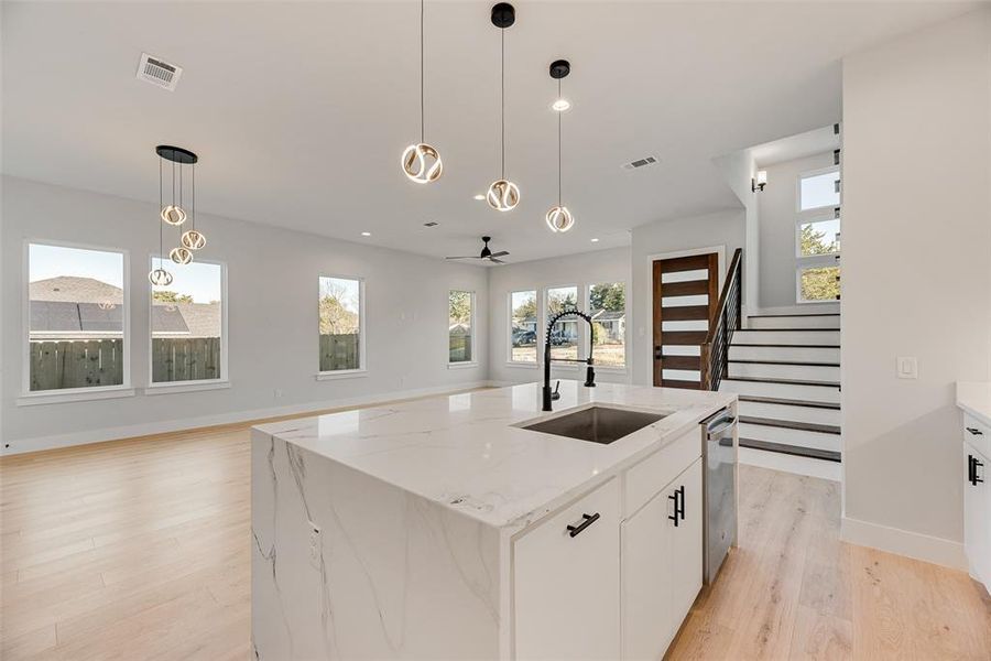 Kitchen with white cabinetry, light wood-style flooring, decorative light fixtures, open floor plan, and recessed lighting Kitchen with white cabinetry, light wood-style flooring, decorative light fixtures, open floor plan, and recessed lighting