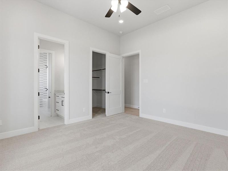 Spacious room featuring light-toned carpet flooring, a ceiling fan with integrated lighting, and multiple doorways