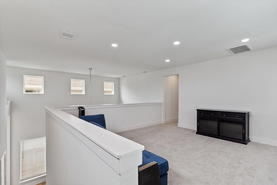 Hall with light carpet, recessed lighting, and an upstairs landing