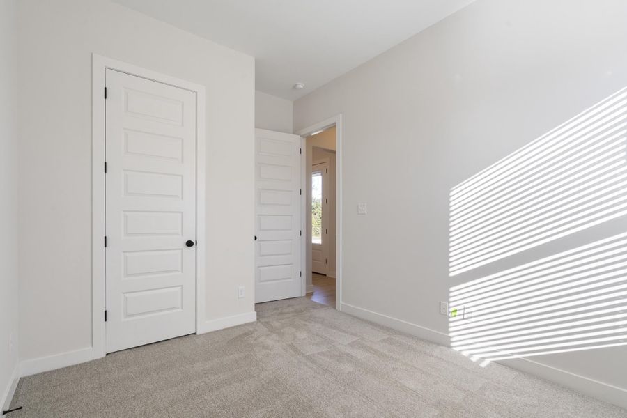 Light gray carpet flooring, white walls, white paneled doors, and ceiling-mounted lighting