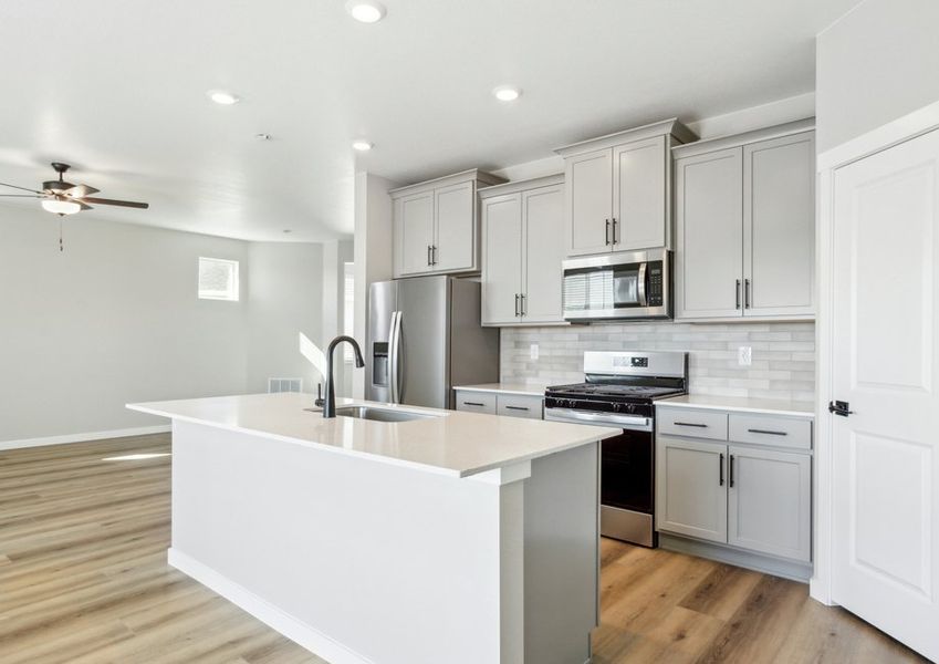 The kitchen has stainless steel appliances and plank flooring.