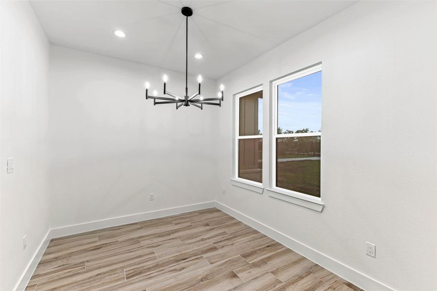 Bright dining area with modern chandelier, wood-style flooring, and large windows offering natural light and a view. Bright dining area with modern chandelier, wood-style flooring, and large windows offering natural light and a view.