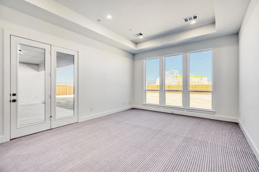 Carpeted empty room with a tray ceiling and recessed lighting