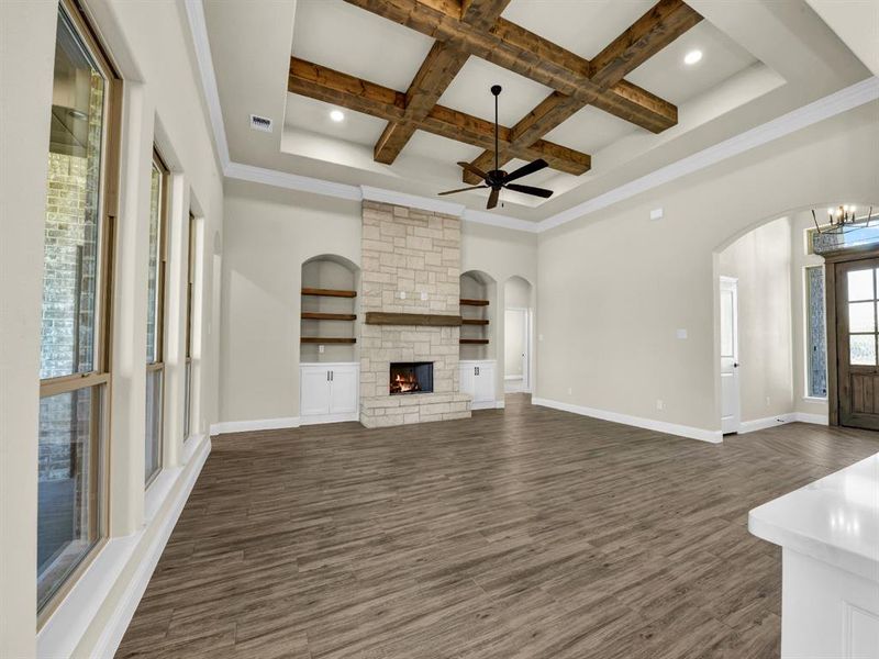 Unfurnished living room featuring beam ceiling, coffered ceiling, dark hardwood / wood-style flooring, built in features, and a fireplace