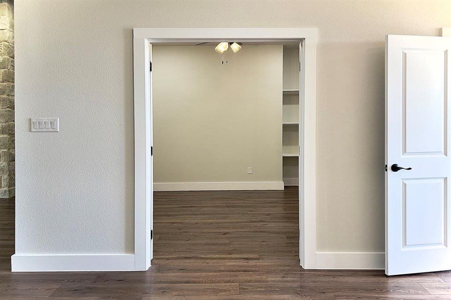 Hall featuring dark flooring and a textured wall
