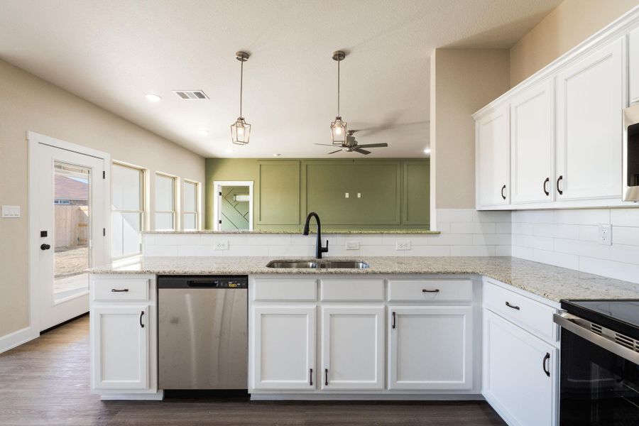 Kitchen with white cabinets, stainless steel appliances, ceiling fan, light stone counters, and a peninsula