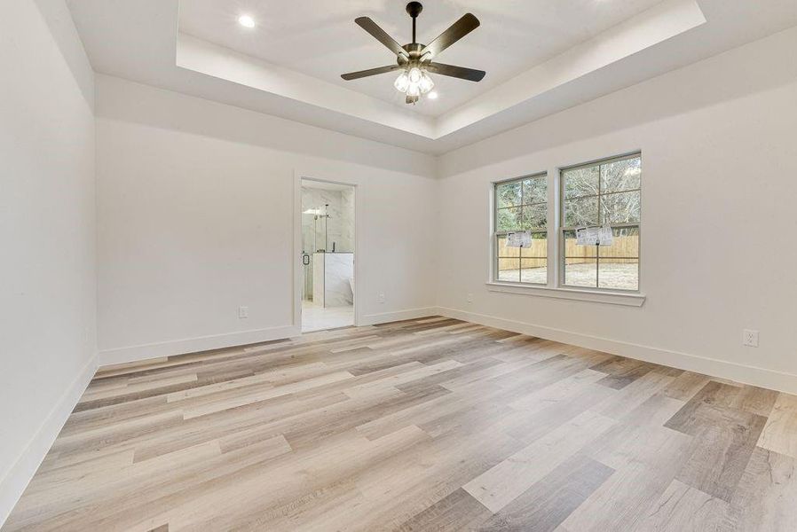 Spare room featuring a tray ceiling, light wood-style floors, recessed lighting, and a ceiling fan Spare room featuring a tray ceiling, light wood-style floors, recessed lighting, and a ceiling fan