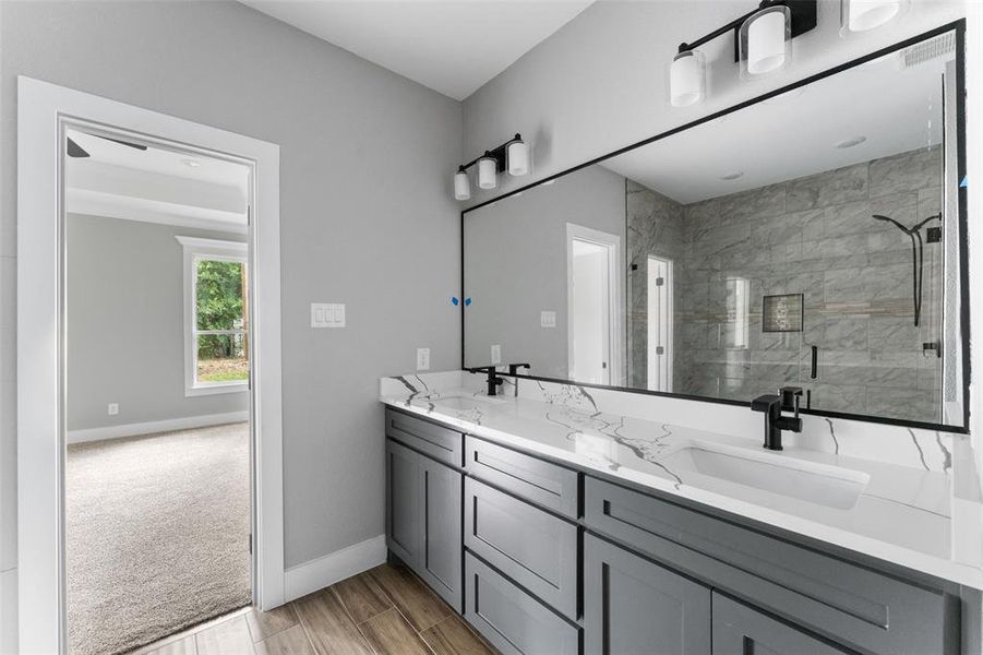 Full bath with a stall shower, double vanity, and wood finish floors