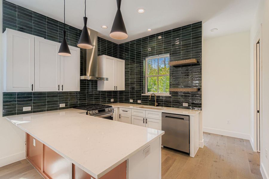 Kitchen featuring recessed lighting, wall chimney range hood, light stone counters, stainless steel appliances, and light wood-style floors Kitchen featuring recessed lighting, wall chimney range hood, light stone counters, stainless steel appliances, and light wood-style floors