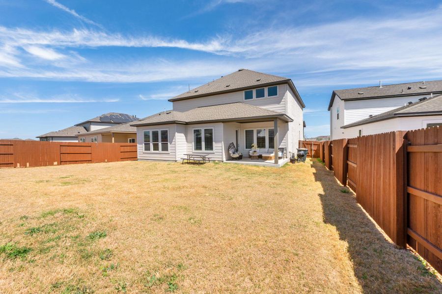 Rear view of house with a patio area, a fenced backyard, and a lawn