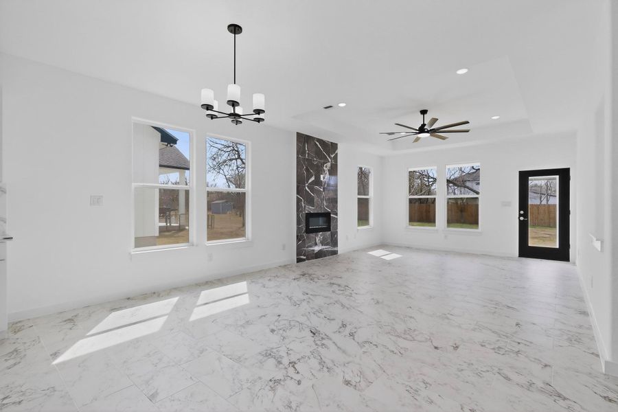 Unfurnished living room with a fireplace, a ceiling fan, suspended lighting,