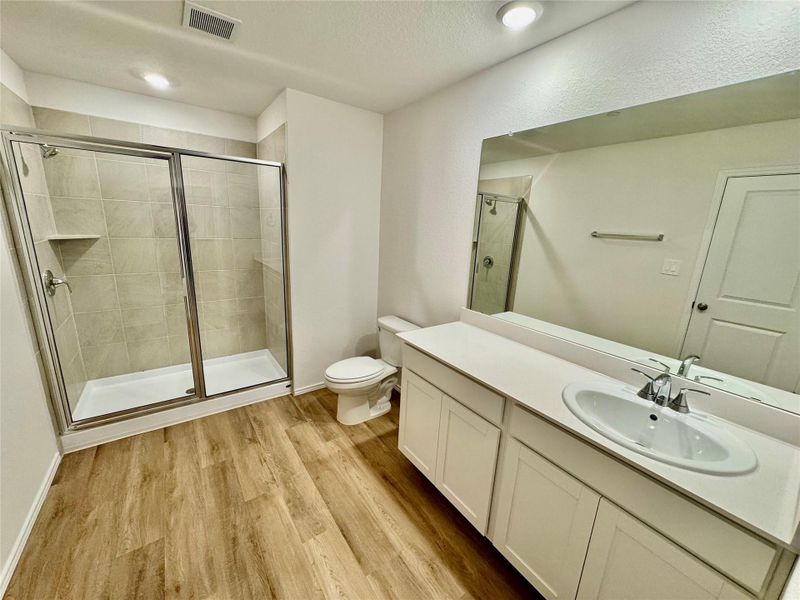 Bathroom with vanity, a stall shower, light wood-type flooring, and a textured ceiling