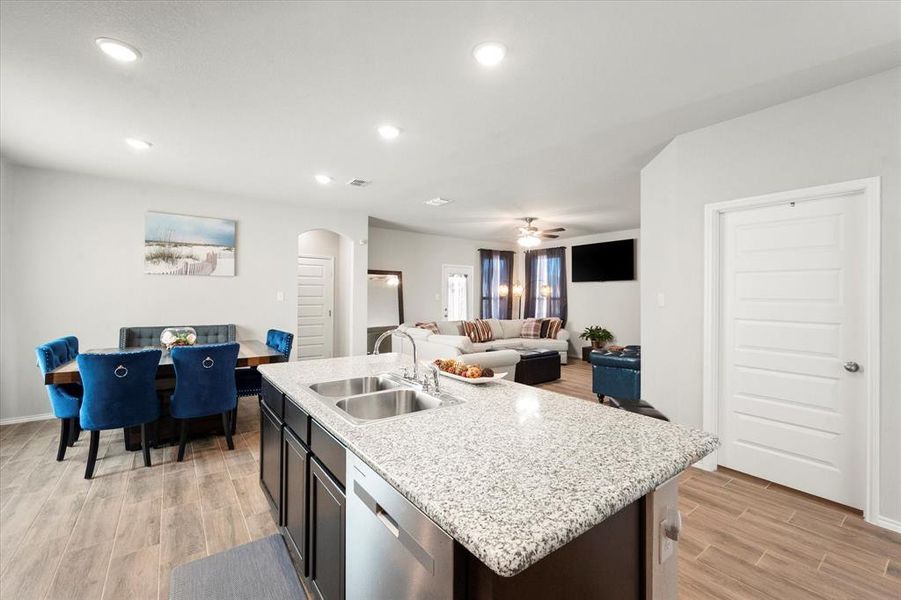 Kitchen with sink, stainless steel dishwasher, ceiling fan, an island with sink, and light hardwood / wood-style floors