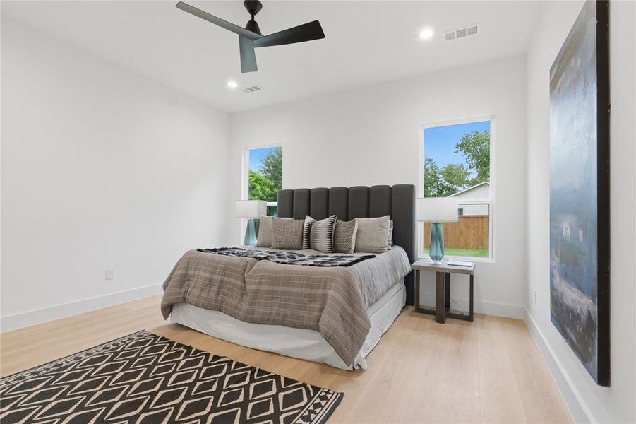 Spacious room featuring light wood-finish flooring, recessed lighting, and a modern ceiling fan Spacious room featuring light wood-finish flooring, recessed lighting, and a modern ceiling fan