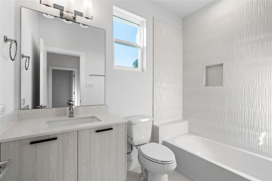 Modern full bath shared by the secondary bedrooms, featuring a floating vanity, large framed mirror & sleek tile surround for a bright, contemporary feel. Modern full bath shared by the secondary bedrooms, featuring a floating vanity, large framed mirror & sleek tile surround for a bright, contemporary feel.