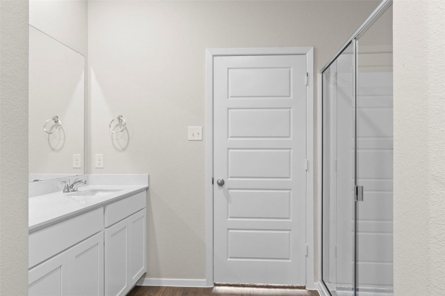 Bathroom featuring vanity, wood finished floors, and a stall shower Bathroom featuring vanity, wood finished floors, and a stall shower