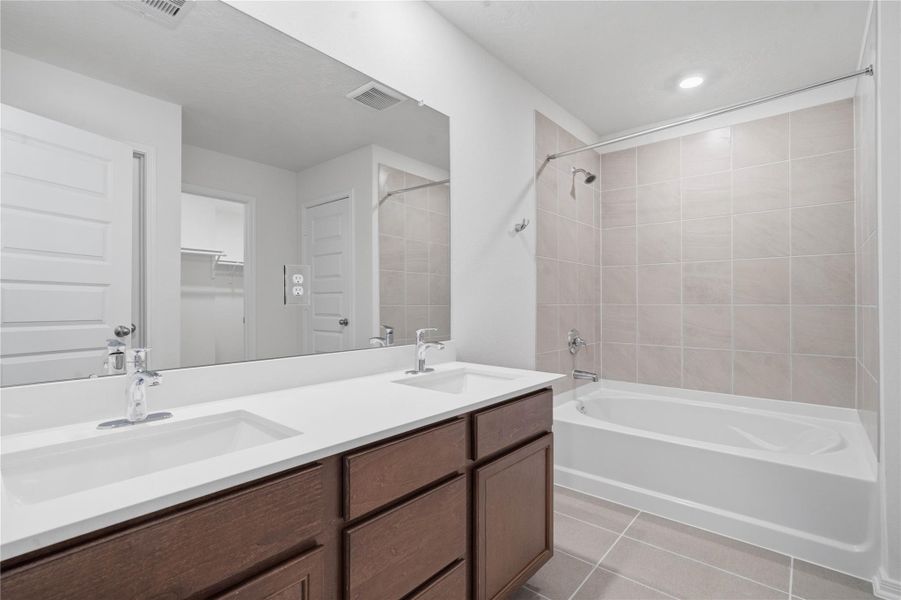 This beautiful primary bathroom is move-in ready! It showcases stained cabinetry paired with light countertops, dual sinks, a large mirror, a spacious walk-in closet with built-in shelving, high ceilings, custom paint, and stylish modern finishes throughout. This beautiful primary bathroom is move-in ready! It showcases stained cabinetry paired with light countertops, dual sinks, a large mirror, a spacious walk-in closet with built-in shelving, high ceilings, custom paint, and stylish modern finishes throughout.