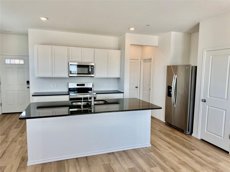 Kitchen with white cabinetry, stainless steel appliances, light wood-style flooring, a kitchen island with sink, and recessed lighting