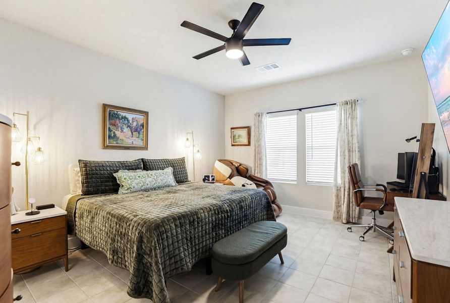 Spacious room featuring tile flooring, a dark-toned ceiling fan with integrated lighting, and two windows with blinds and drapery