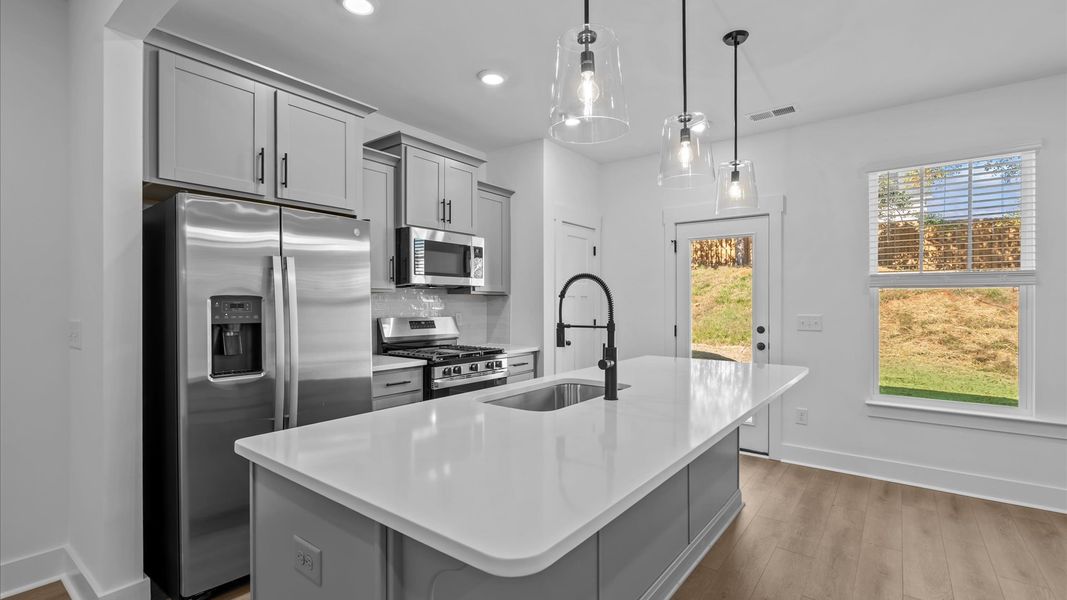 Highly skilled kitchen design includes a 9-foot island, quartz countertops, and stylish pendant fixtures