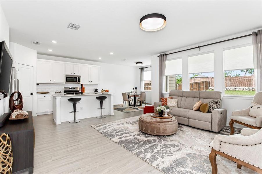 Open-concept living space featuring light-toned flooring, white walls, and recessed lighting