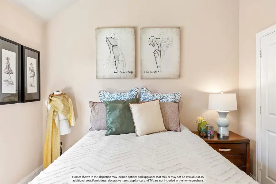 Bedroom with white bedding, colorful pillows, wood nightstand, and fashion sketch wall art on beige walls