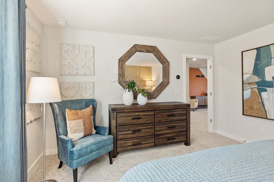 A bedroom with a mirror and a chair.