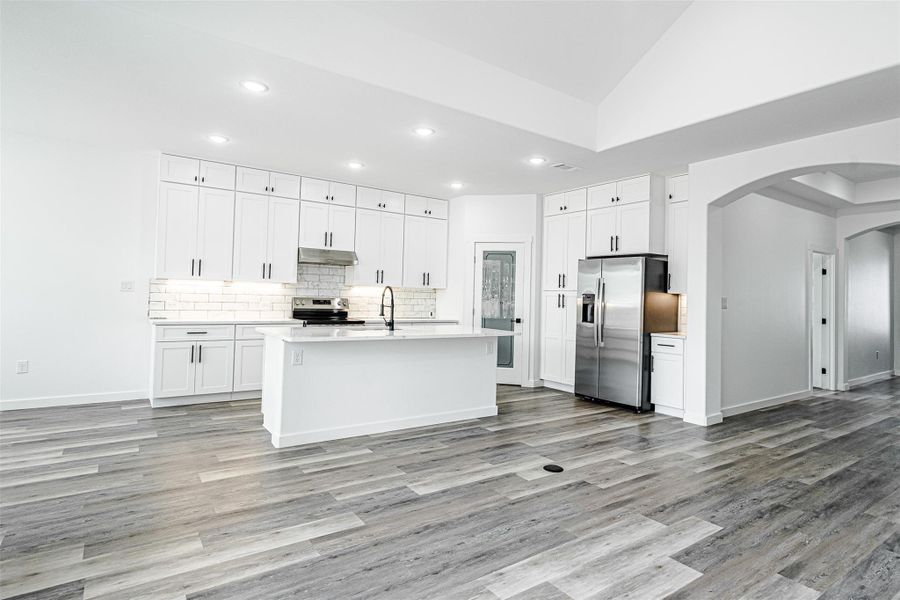 A well-appointed kitchen showcasing an island, crisp white cabinetry, and modern appliances. A well-appointed kitchen showcasing an island, crisp white cabinetry, and modern appliances.