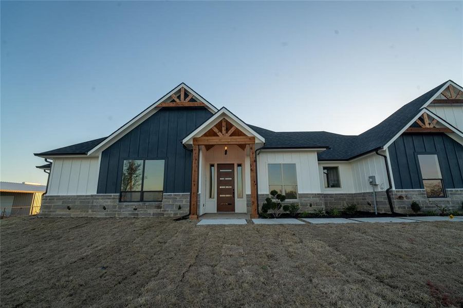 Modern inspired farmhouse with stone siding, board and batten siding, and roof with shingles