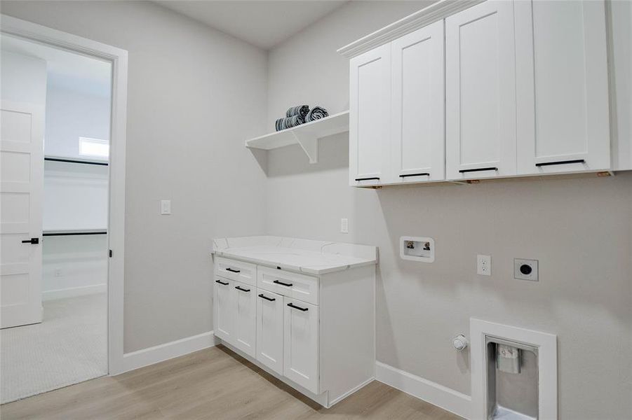 Laundry area featuring hookup for a washing machine, hookup for a gas dryer, light wood-style flooring, cabinet space, and electric dryer hookup Laundry area featuring hookup for a washing machine, hookup for a gas dryer, light wood-style flooring, cabinet space, and electric dryer hookup