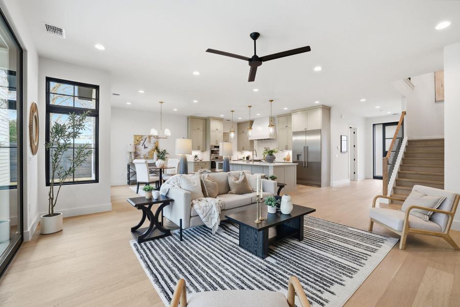 Living area with light wood-type flooring, ceiling fan, and a chandelier