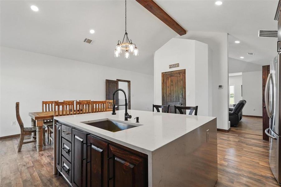 Kitchen featuring light stone counters, recessed lighting, dark brown cabinetry, hanging light fixtures, and dark wood-style flooring Kitchen featuring light stone counters, recessed lighting, dark brown cabinetry, hanging light fixtures, and dark wood-style flooring