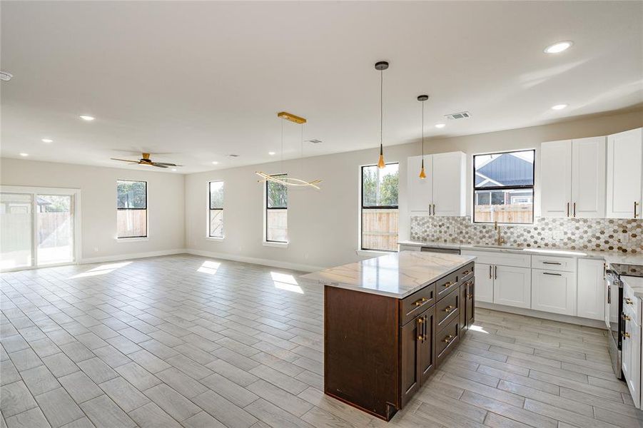 Kitchen with decorative light fixtures, white cabinetry, ceiling fan, and tasteful backsplash