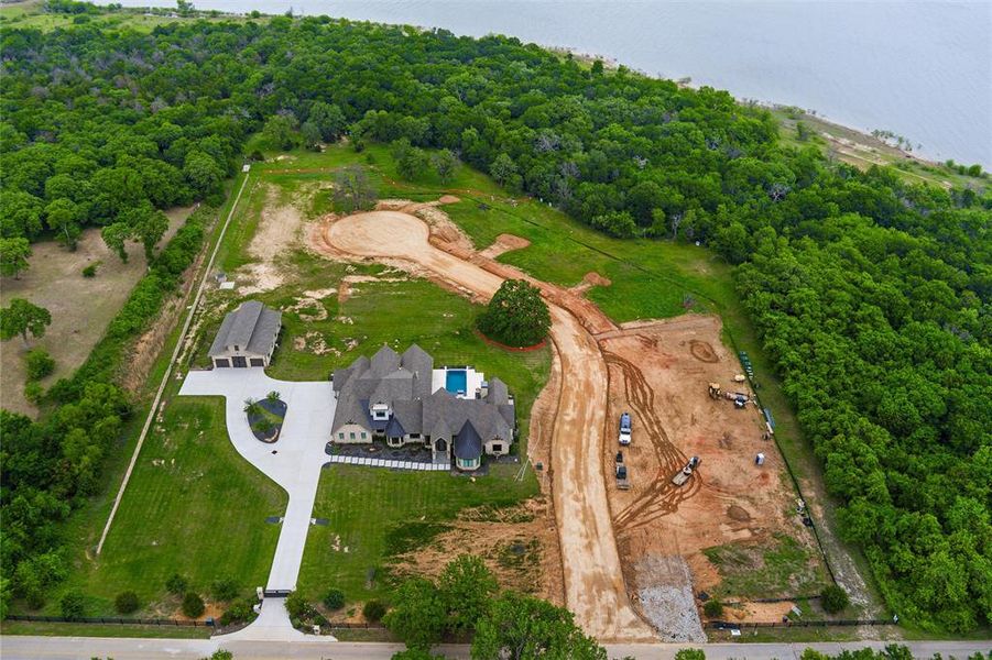 Expansive residential property featuring a large residence with a multi-gabled roofline, an attached three-car garage, and an in-ground swimming pool Expansive residential property featuring a large residence with a multi-gabled roofline, an attached three-car garage, and an in-ground swimming pool