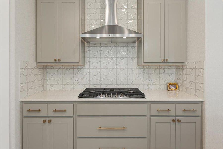 Kitchen featuring gray cabinetry, light stone countertops, stainless steel gas stovetop, and decorative backsplash