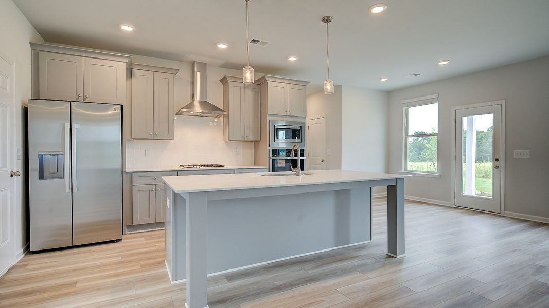 Meridian II kitchen with white tile backsplash, large center island, and view of breakfast area and family room at Brighton.