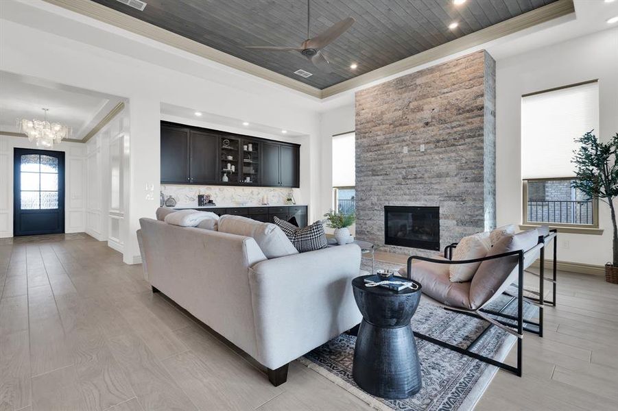 Living area with a raised ceiling, wooden ceiling, light wood-style flooring, and a fireplace