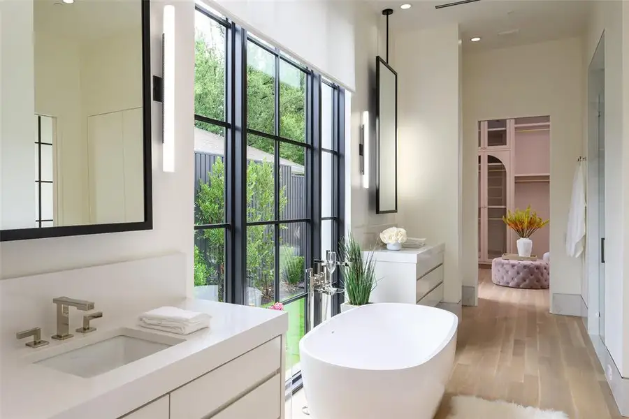 Bathroom featuring a walk in closet, a freestanding tub, vanity, light wood-style flooring, and recessed lighting Bathroom featuring a walk in closet, a freestanding tub, vanity, light wood-style flooring, and recessed lighting