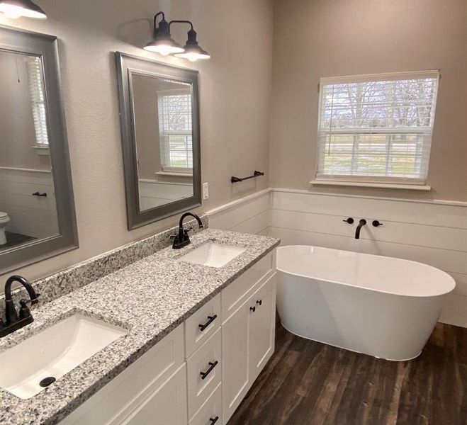 Bathroom with vanity, hardwood / wood-style floors, and a bath