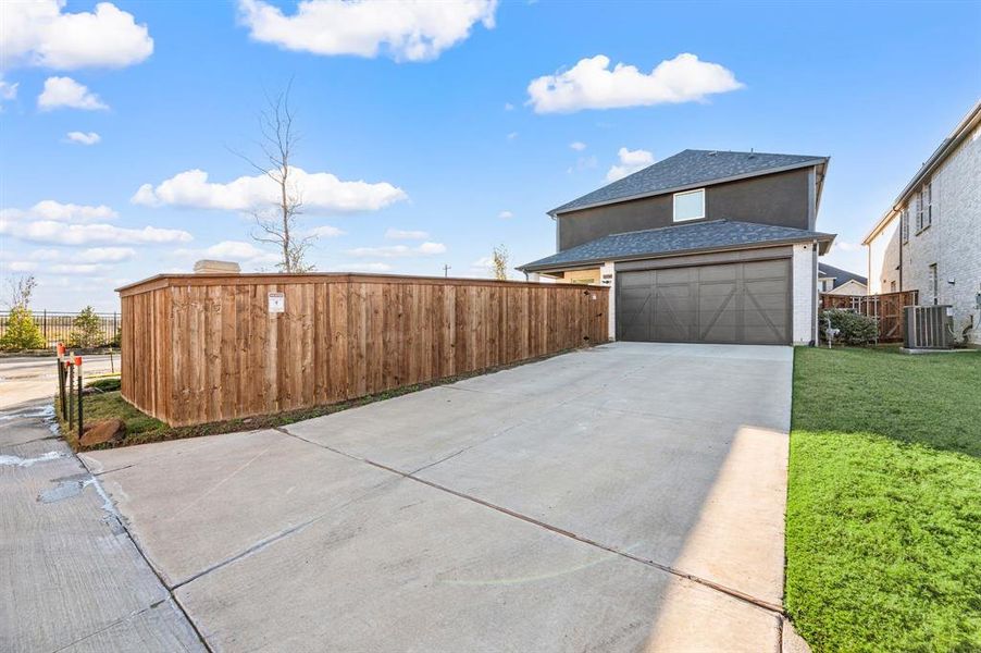 View of property exterior with a shingled roof and concrete driveway