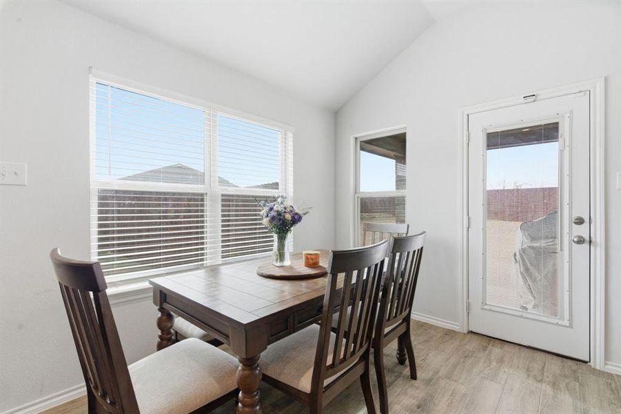 Dining area with light wood finished floors and vaulted ceiling