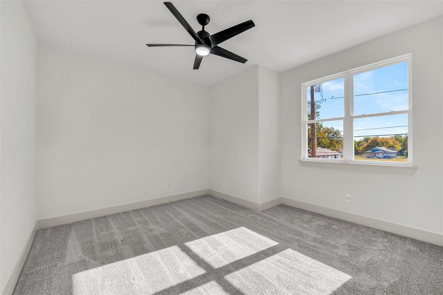 Empty room featuring light carpet and a ceiling fan